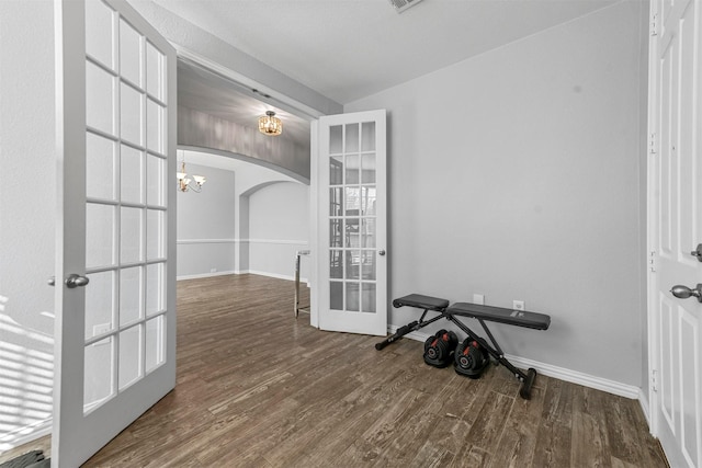 exercise room with hardwood / wood-style floors, a notable chandelier, and french doors