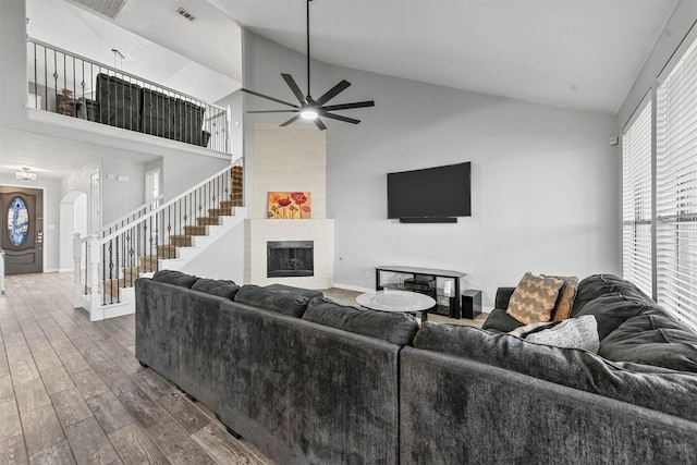 living room with a fireplace, wood-type flooring, high vaulted ceiling, and ceiling fan