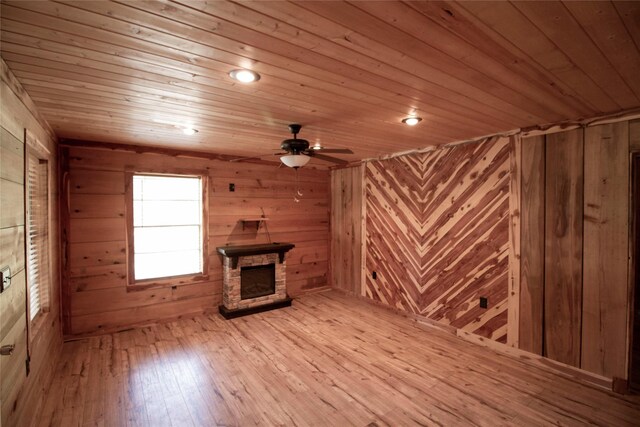 unfurnished living room with wooden walls, ceiling fan, a fireplace, wood-type flooring, and wood ceiling