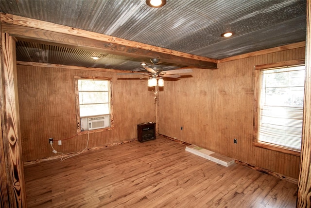 unfurnished room with hardwood / wood-style floors, ceiling fan, plenty of natural light, and wood walls