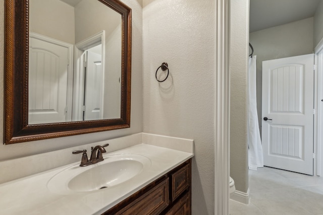 bathroom with tile patterned flooring, vanity, and toilet