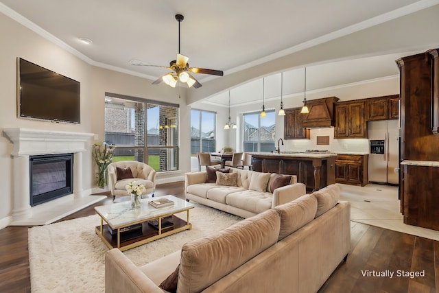 living room with hardwood / wood-style floors, ceiling fan with notable chandelier, crown molding, and sink