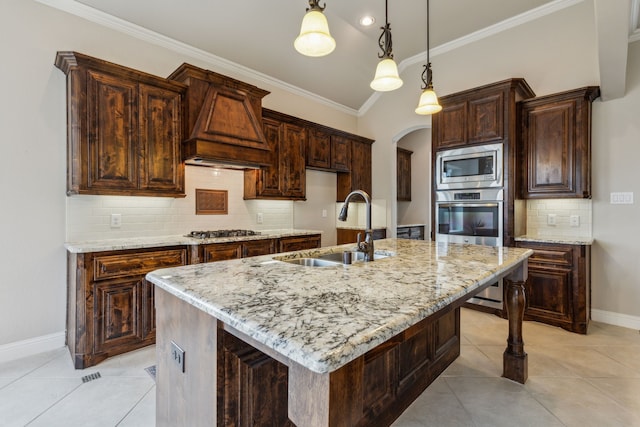 kitchen featuring light stone counters, a center island with sink, appliances with stainless steel finishes, and sink