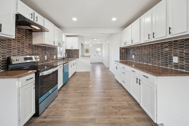 kitchen with stainless steel appliances, white cabinetry, hardwood / wood-style flooring, and dark stone countertops