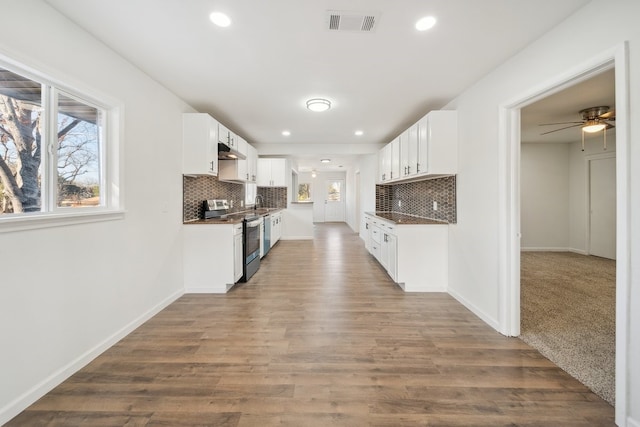 kitchen featuring white cabinets, wood-type flooring, decorative backsplash, and stainless steel range with electric cooktop