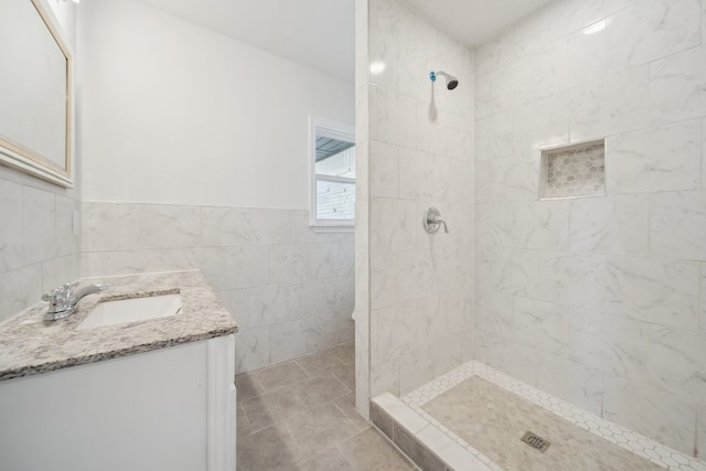 bathroom with tile patterned floors, vanity, tile walls, and tiled shower