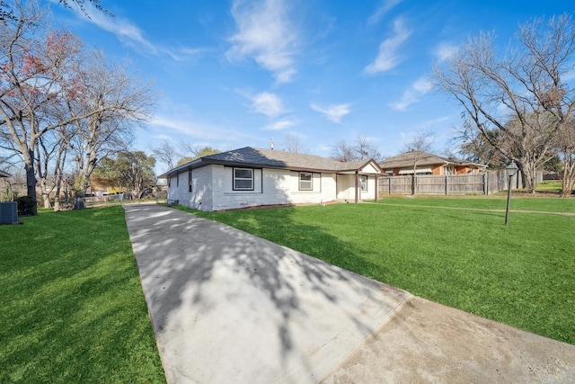 view of front of property featuring brick siding, fence, and a front lawn