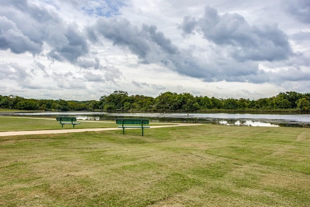 surrounding community with a water view and a yard