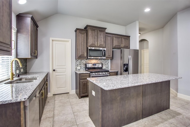 kitchen with light stone counters, sink, a kitchen island, and appliances with stainless steel finishes