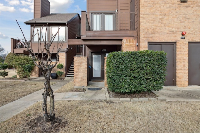 exterior space featuring brick siding, a chimney, and a balcony