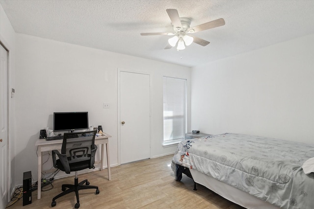 bedroom featuring light wood finished floors, a textured ceiling, and ceiling fan