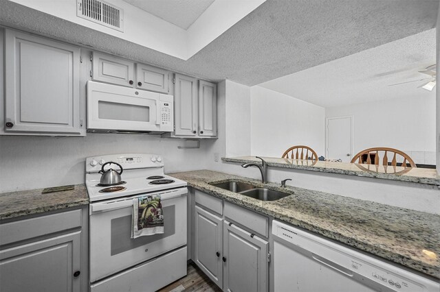 kitchen with visible vents, gray cabinets, white appliances, and a sink