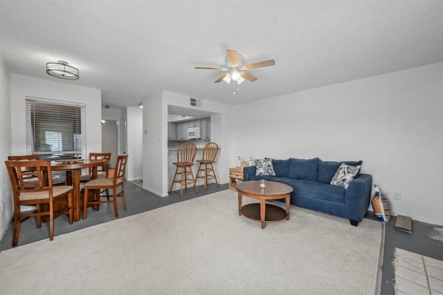 living room featuring ceiling fan and a textured ceiling