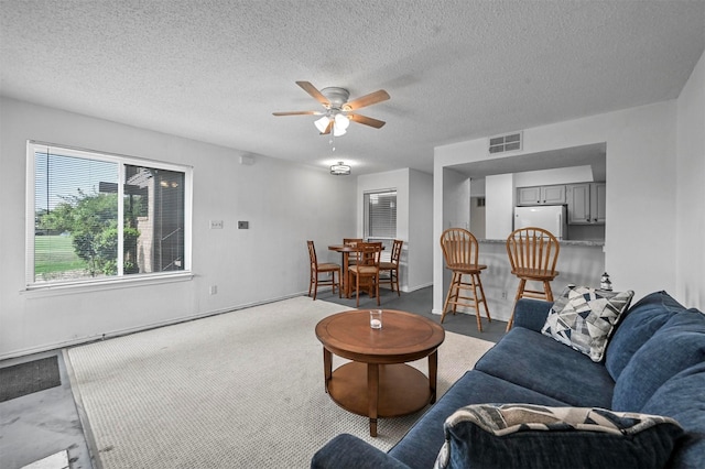 living room featuring a textured ceiling and ceiling fan