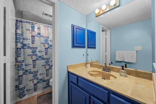 bathroom with vanity, a shower with shower curtain, visible vents, a textured ceiling, and toilet