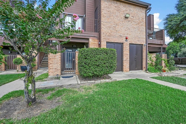 exterior space with a front lawn, brick siding, and a balcony