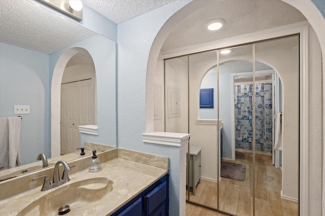 bathroom featuring a textured ceiling, vanity, and wood finished floors