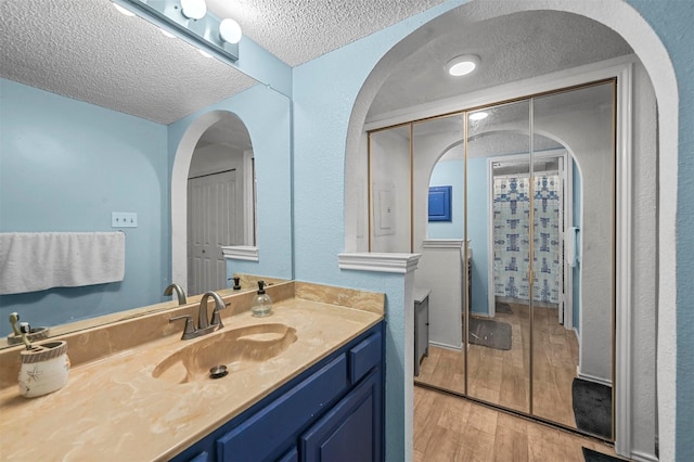 bathroom with a shower, wood-type flooring, vanity, and a textured ceiling