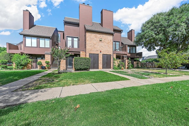 exterior space with brick siding, a lawn, and a balcony