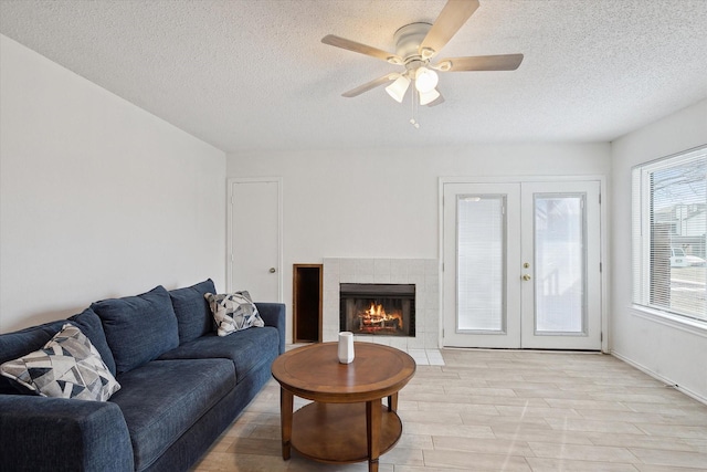 living room with a textured ceiling, french doors, light wood-type flooring, and ceiling fan