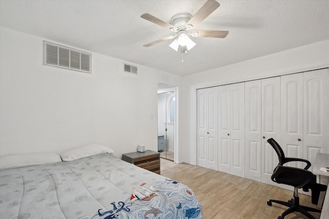 bedroom featuring light wood-style flooring, visible vents, a closet, and a textured ceiling