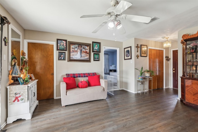 sitting room with ceiling fan with notable chandelier and dark hardwood / wood-style floors