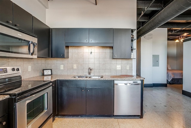 kitchen featuring light stone countertops, appliances with stainless steel finishes, sink, and electric panel