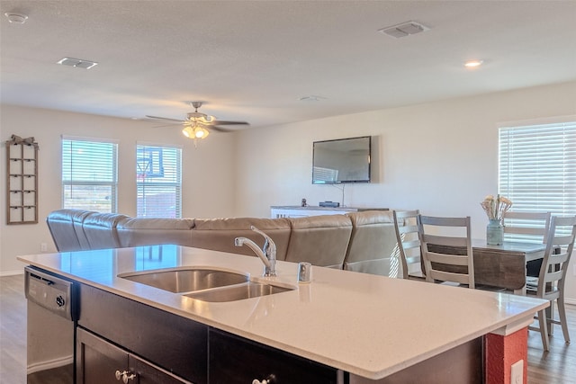 kitchen featuring dishwasher, a center island with sink, sink, ceiling fan, and light wood-type flooring