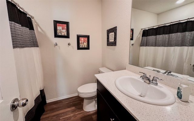 bathroom with wood-type flooring, toilet, vanity, and walk in shower