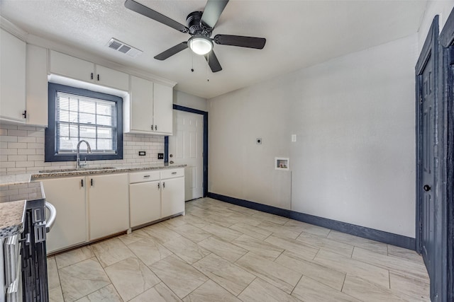 kitchen with light stone countertops, backsplash, ceiling fan, sink, and white cabinets