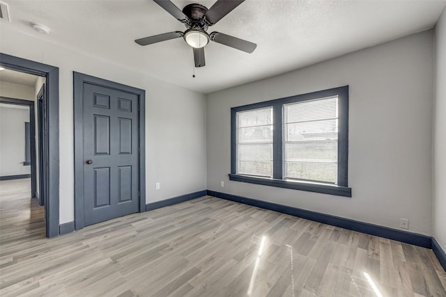 empty room with ceiling fan and light hardwood / wood-style floors