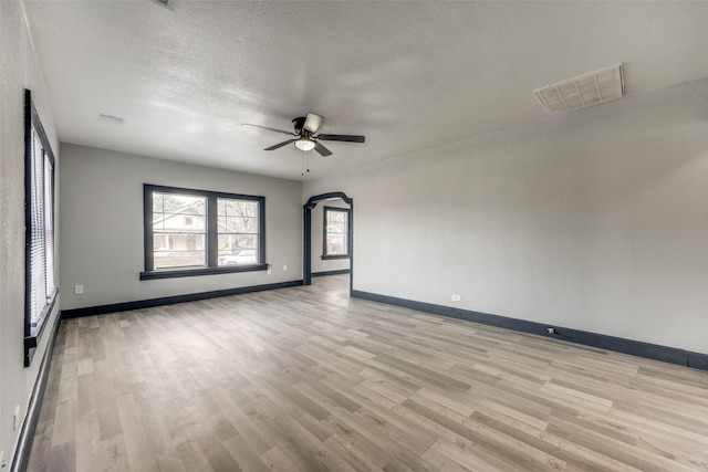 empty room with ceiling fan, light hardwood / wood-style floors, and a textured ceiling