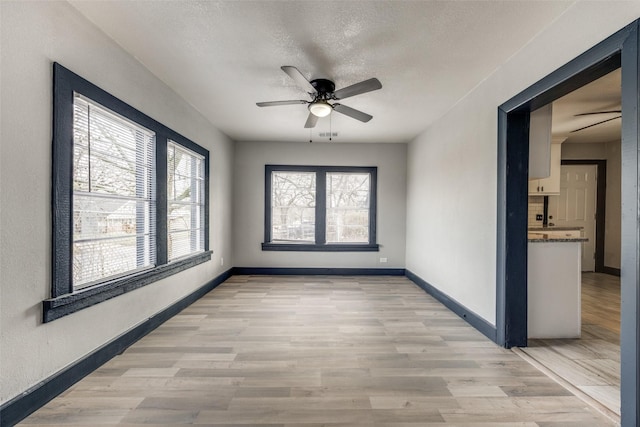 empty room with ceiling fan, light hardwood / wood-style floors, and a textured ceiling