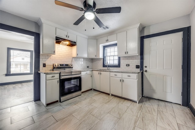 kitchen with sink, light stone counters, stainless steel electric stove, decorative backsplash, and white cabinets