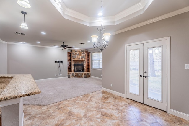 unfurnished living room with ceiling fan with notable chandelier, a fireplace, light colored carpet, and crown molding