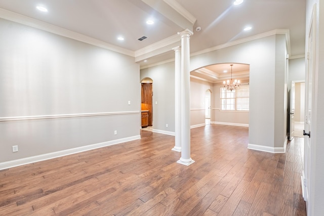 unfurnished room featuring hardwood / wood-style flooring, ornate columns, crown molding, and an inviting chandelier