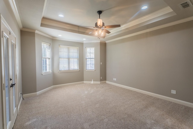 carpeted spare room featuring a tray ceiling, crown molding, and ceiling fan