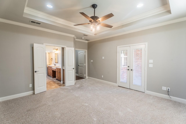 unfurnished bedroom featuring ceiling fan, a raised ceiling, ensuite bathroom, and french doors