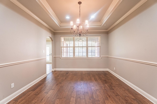 spare room featuring a tray ceiling, an inviting chandelier, dark hardwood / wood-style floors, and crown molding