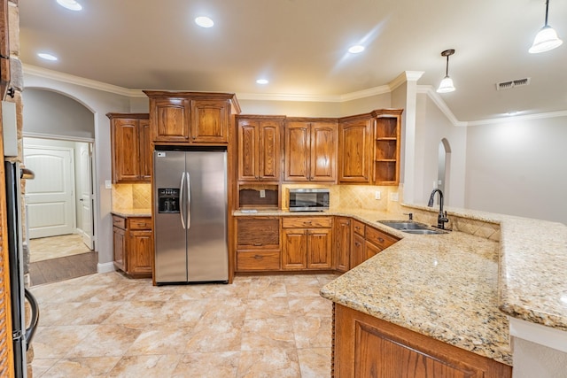 kitchen featuring sink, hanging light fixtures, light stone countertops, appliances with stainless steel finishes, and kitchen peninsula