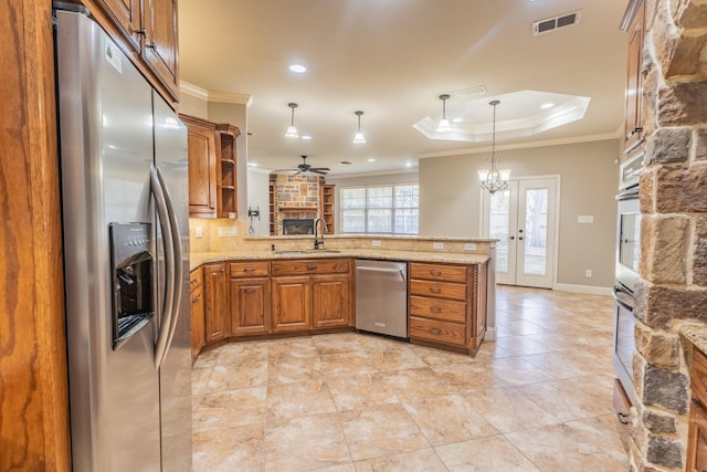 kitchen with kitchen peninsula, appliances with stainless steel finishes, pendant lighting, and ornamental molding