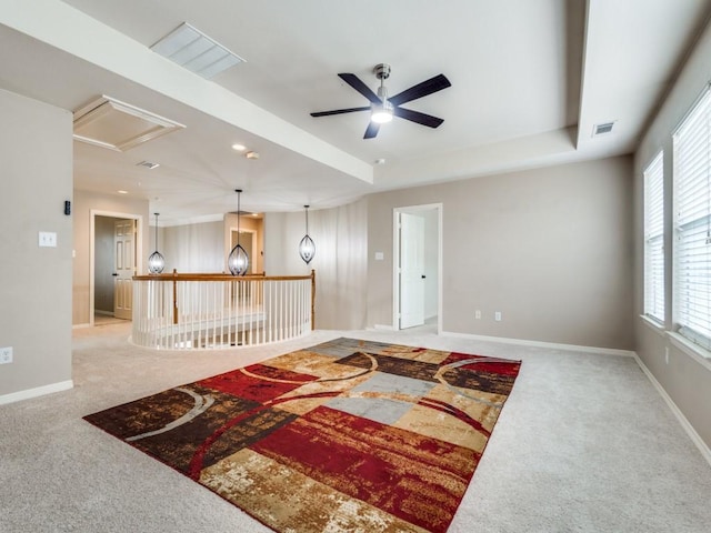 living room featuring a raised ceiling, ceiling fan, and light colored carpet