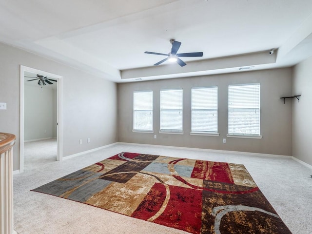 carpeted living room featuring a raised ceiling and ceiling fan