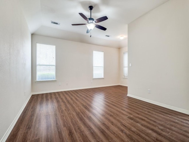 empty room with dark hardwood / wood-style floors, a wealth of natural light, and ceiling fan