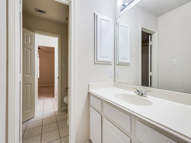 bathroom with toilet, vanity, and tile patterned floors