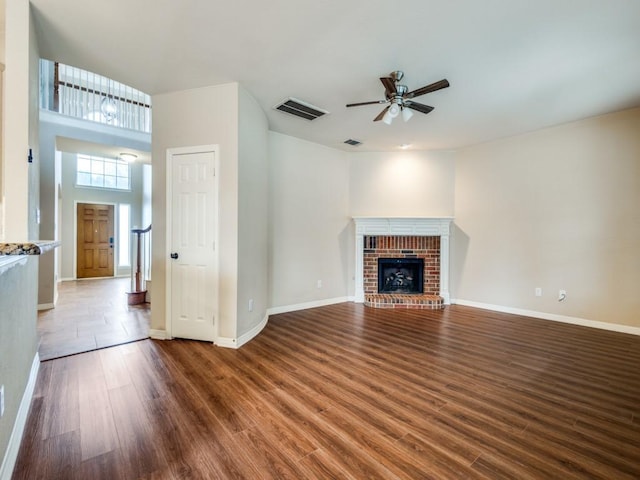 unfurnished living room featuring a fireplace, ceiling fan, and dark wood-type flooring