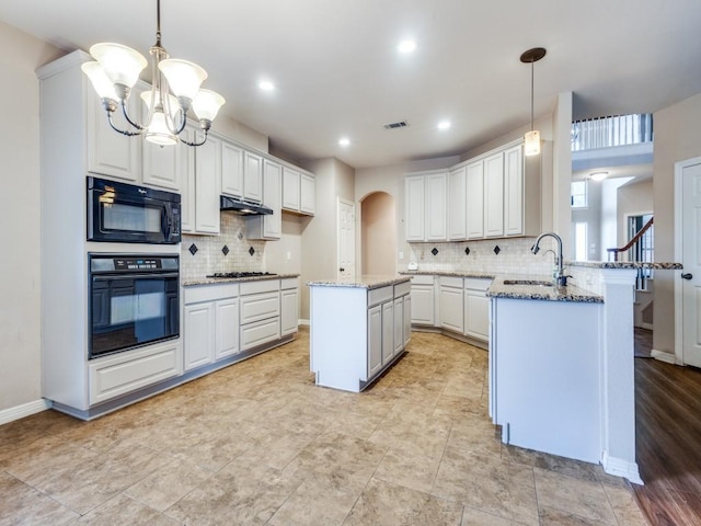 kitchen with hanging light fixtures, kitchen peninsula, sink, and black appliances