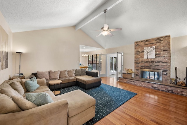 living room featuring light hardwood / wood-style floors, a textured ceiling, beam ceiling, and a brick fireplace