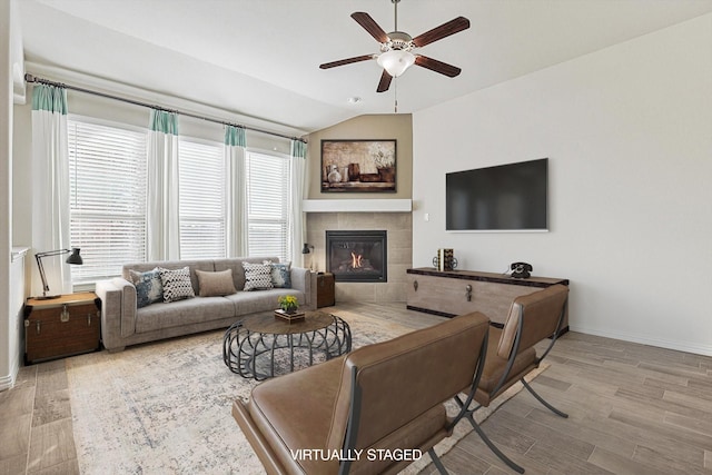 living room with ceiling fan, a fireplace, and vaulted ceiling