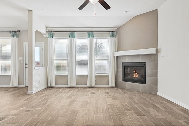 unfurnished living room with a tile fireplace, light hardwood / wood-style flooring, ceiling fan, and lofted ceiling